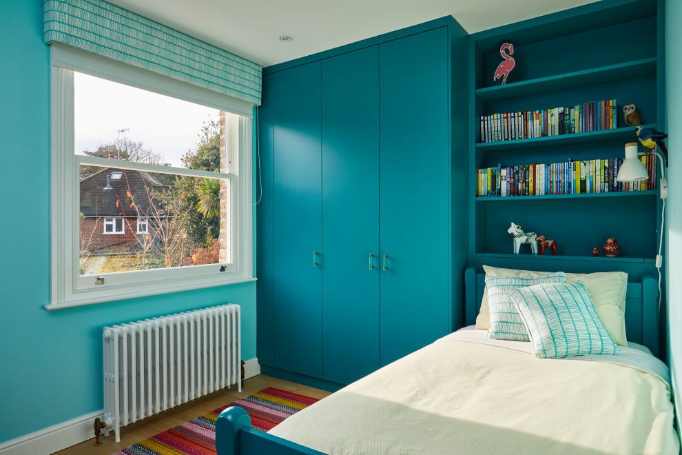 Inspiration for a small contemporary children’s room for girls in Surrey with blue walls, light hardwood flooring and brown floors.