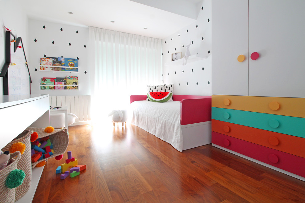 Modelo de dormitorio infantil de 1 a 3 años actual de tamaño medio con paredes blancas, suelo laminado y suelo marrón