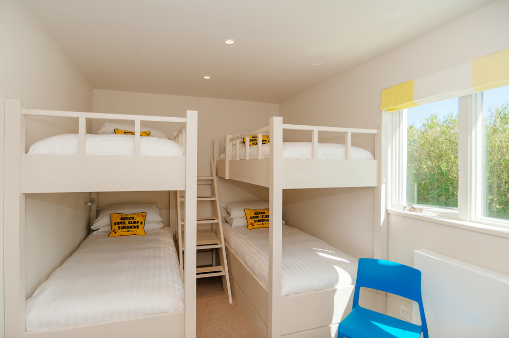 Réalisation d'une chambre d'enfant marine avec un mur beige, parquet clair et un lit superposé.