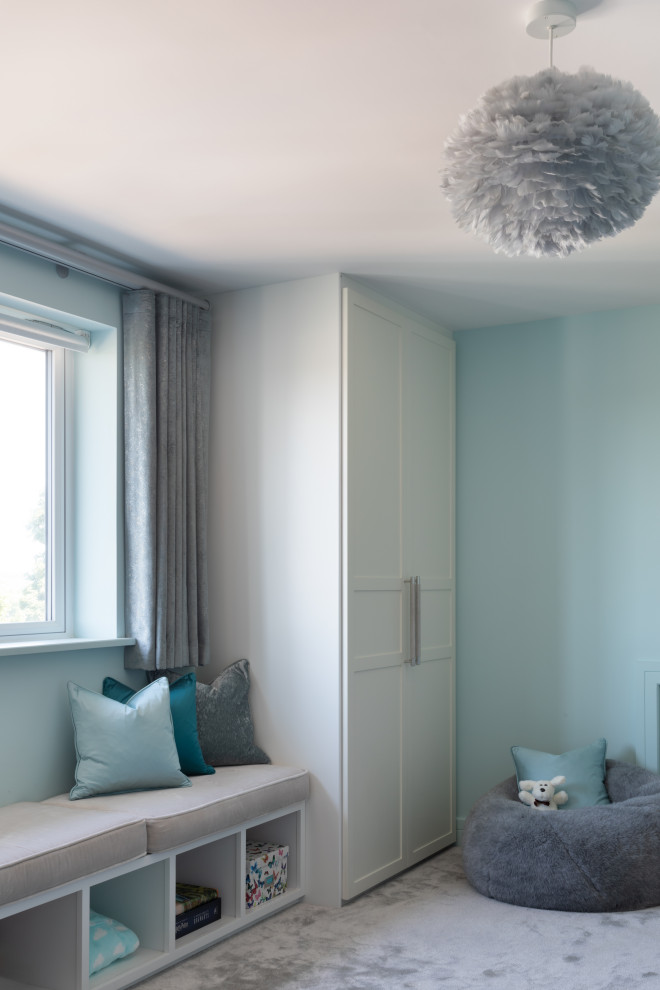 Inredning av ett modernt mellanstort barnrum kombinerat med sovrum, med blå väggar, heltäckningsmatta och grått golv