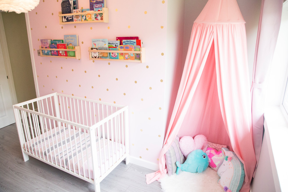 Foto di una cameretta per bambini da 1 a 3 anni minimal di medie dimensioni con pareti rosa e pavimento in laminato