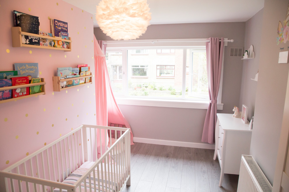Modelo de dormitorio infantil de 1 a 3 años contemporáneo de tamaño medio con paredes rosas y suelo laminado