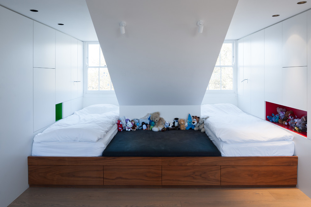 Photo of a small contemporary gender neutral children’s room in London with white walls and light hardwood flooring.