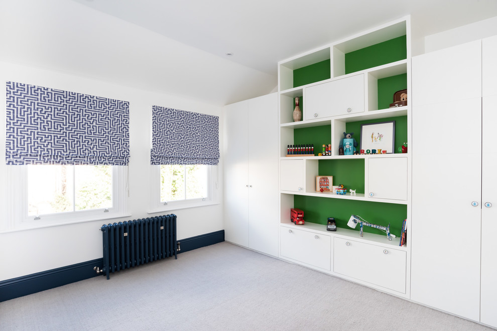 This is an example of a large modern children’s room for boys in London with white walls, carpet and beige floors.
