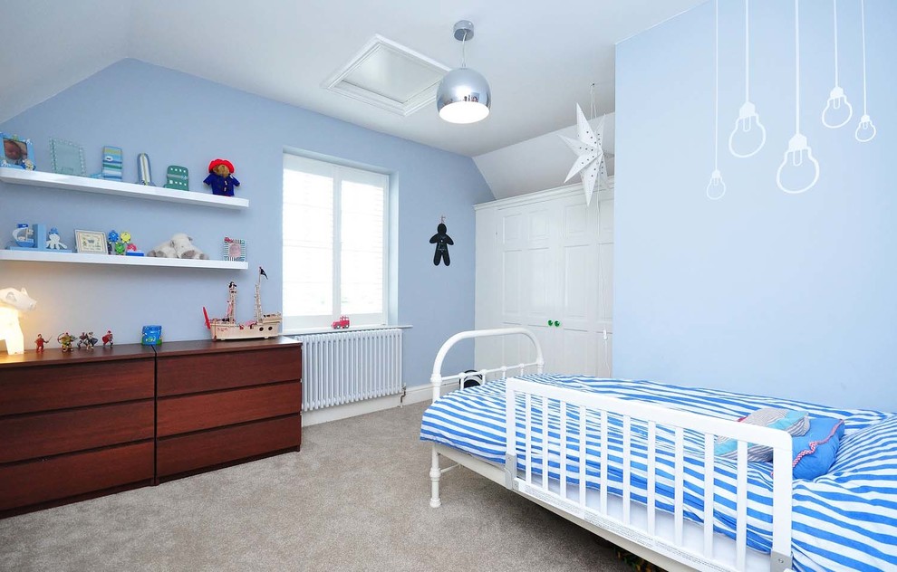 Inredning av ett modernt könsneutralt småbarnsrum kombinerat med sovrum, med blå väggar och heltäckningsmatta