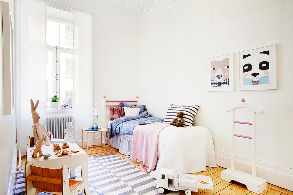 Immagine di una cameretta per bambini da 4 a 10 anni nordica di medie dimensioni con pareti bianche e pavimento in legno massello medio