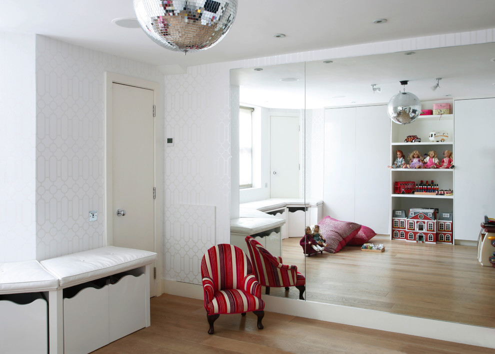 This is an example of a contemporary children’s room for girls in Dorset with white walls and medium hardwood flooring.