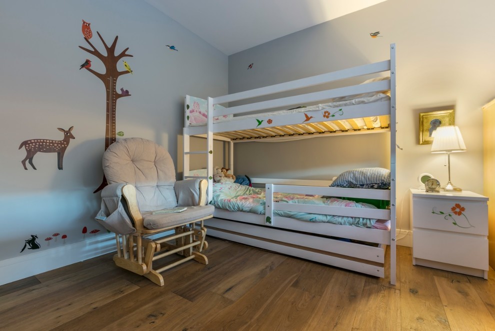 Immagine di una cameretta per bambini chic con pareti grigie, pavimento in legno massello medio e pavimento marrone