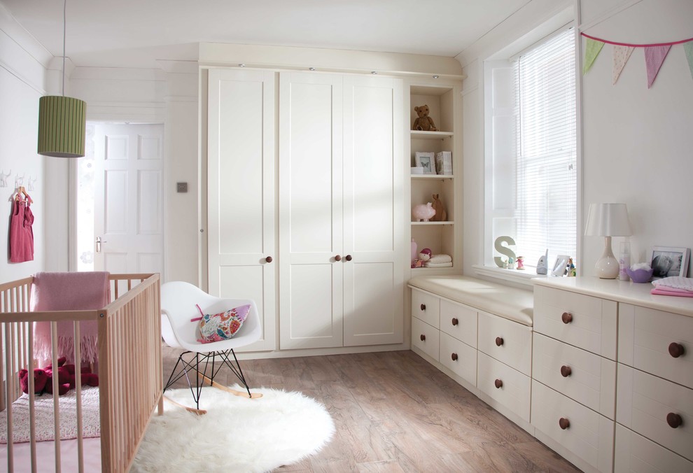 Inredning av ett klassiskt småbarnsrum kombinerat med sovrum, med vita väggar och mellanmörkt trägolv