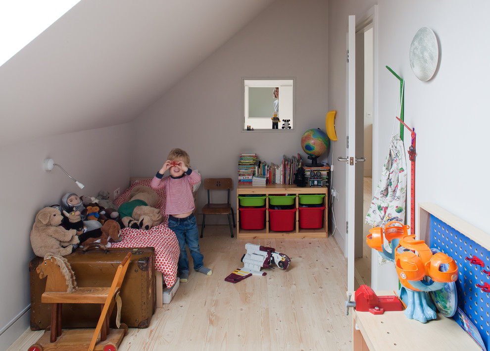 Small scandinavian children’s room for boys in London with white walls and light hardwood flooring.
