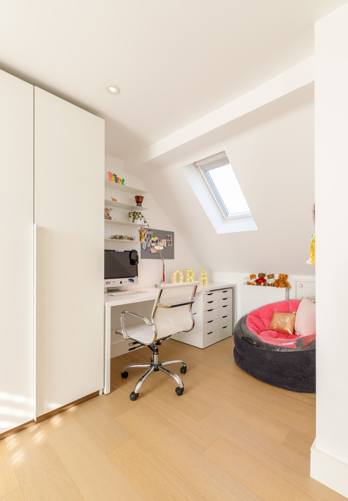 Photo of a contemporary kids' bedroom for girls in London with white walls, light hardwood flooring and beige floors.