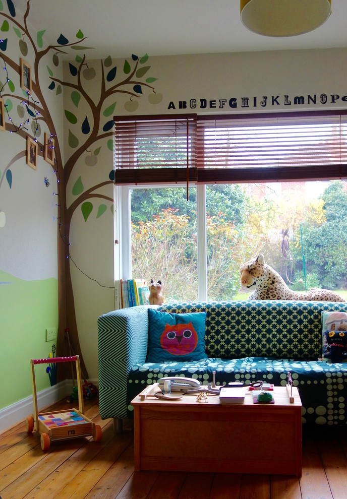 Cette photo montre une petite chambre d'enfant de 1 à 3 ans éclectique avec un mur multicolore et un sol en bois brun.