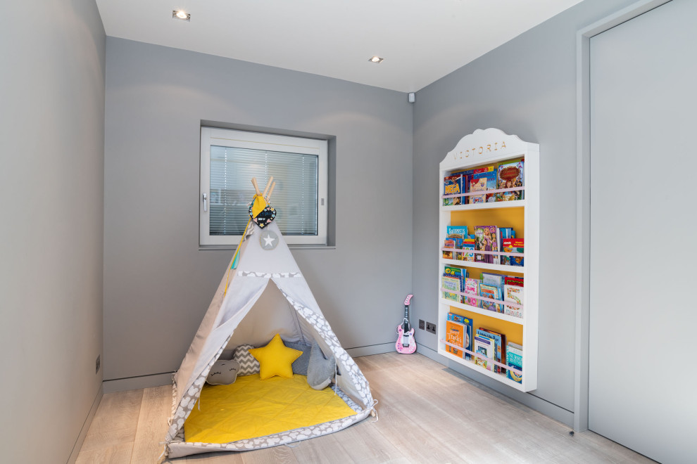 Bild på ett mellanstort funkis barnrum kombinerat med lekrum, med grå väggar, ljust trägolv och beiget golv
