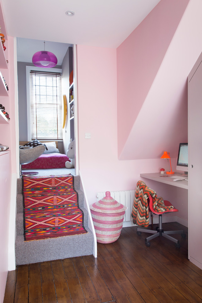 Ejemplo de habitación de niña de 4 a 10 años actual pequeña con escritorio, paredes rosas y suelo de madera oscura