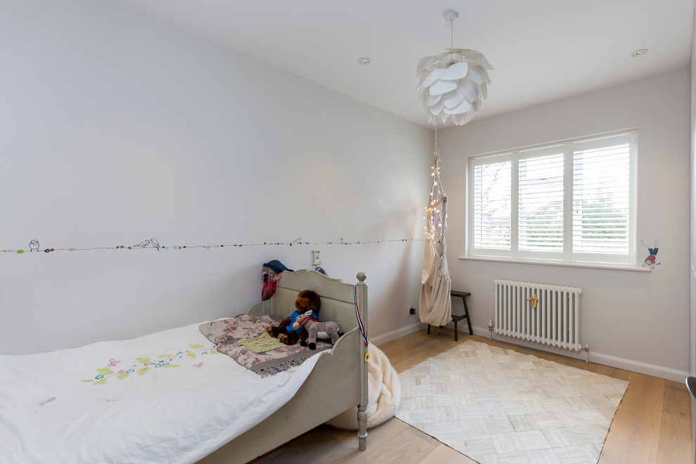 Contemporary gender neutral kids' study space in London with multi-coloured walls and light hardwood flooring.