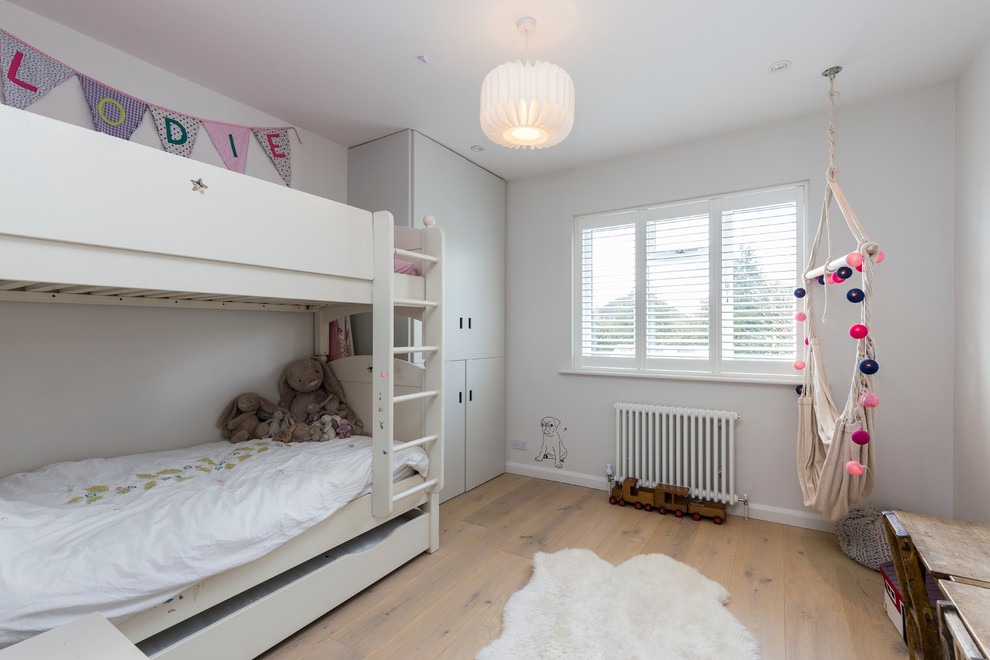 Exemple d'une chambre neutre tendance avec un bureau, un mur multicolore et parquet clair.