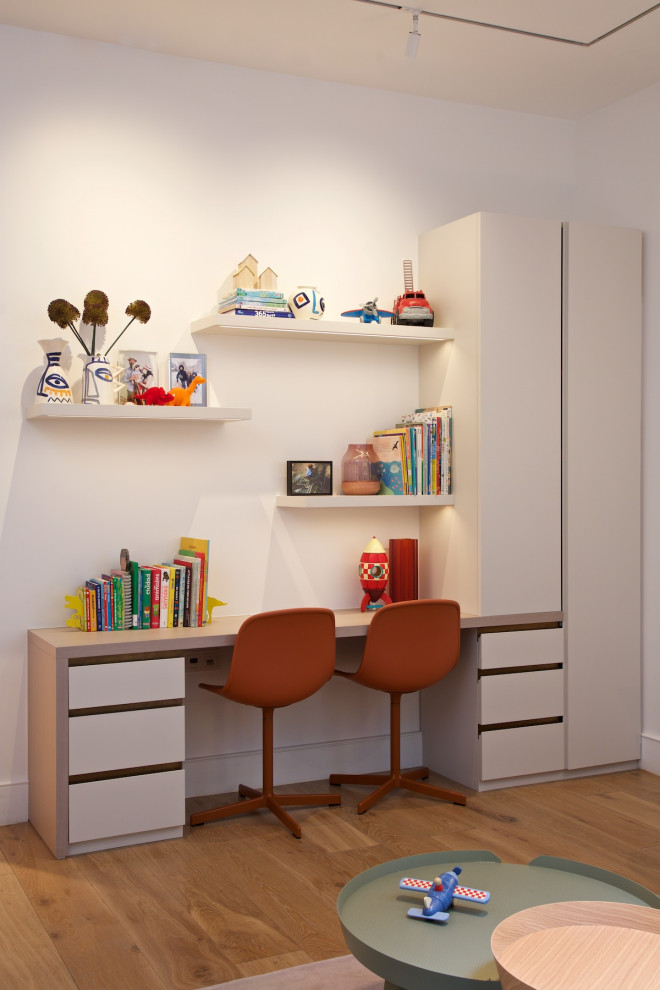 Bild på ett mellanstort funkis könsneutralt barnrum kombinerat med skrivbord och för 4-10-åringar, med vita väggar, mellanmörkt trägolv och brunt golv