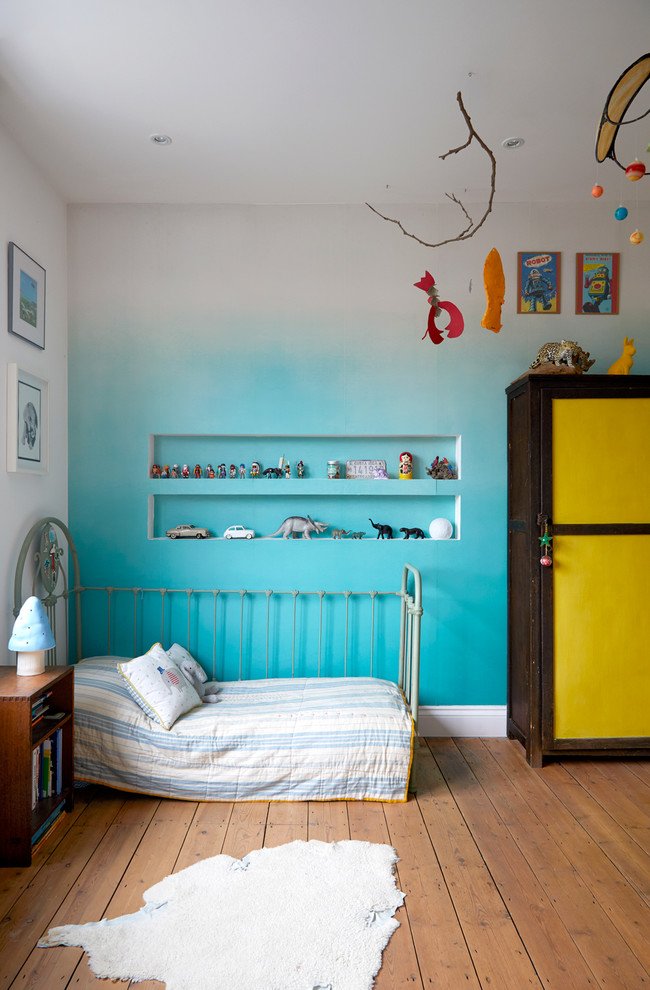 Idées déco pour une chambre d'enfant de 1 à 3 ans éclectique avec un mur bleu, un sol en bois brun et un sol marron.