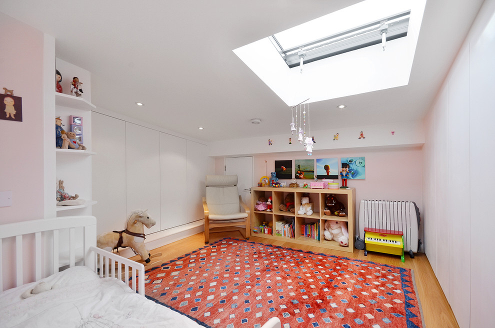 Ispirazione per una cameretta per bambini da 1 a 3 anni chic con pareti rosa e parquet chiaro