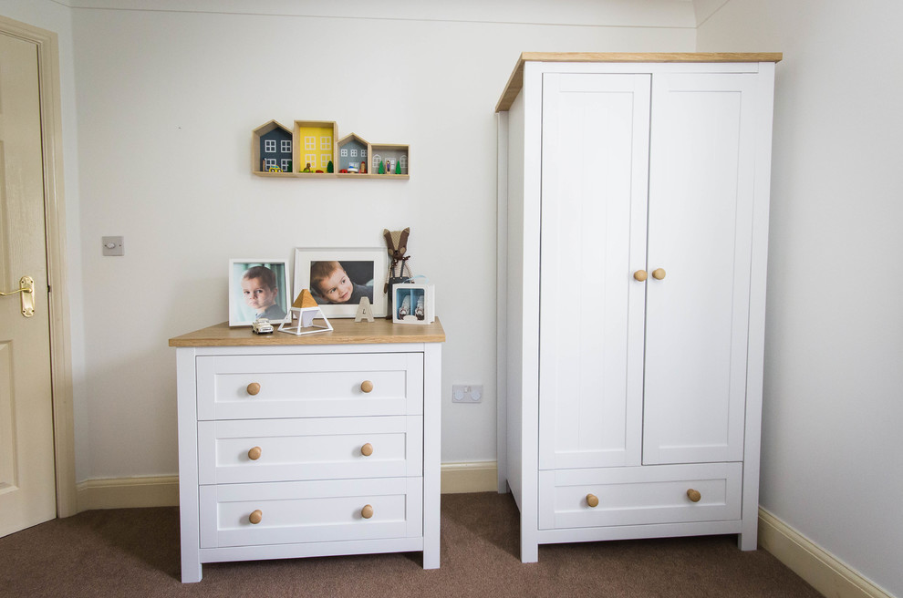 Photo of a small scandinavian gender neutral toddler’s room in Berkshire with white walls, carpet and brown floors.