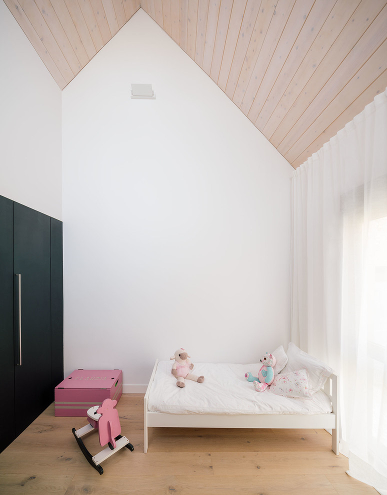 Imagen de dormitorio infantil de 4 a 10 años actual de tamaño medio con paredes blancas, suelo de madera en tonos medios y suelo marrón