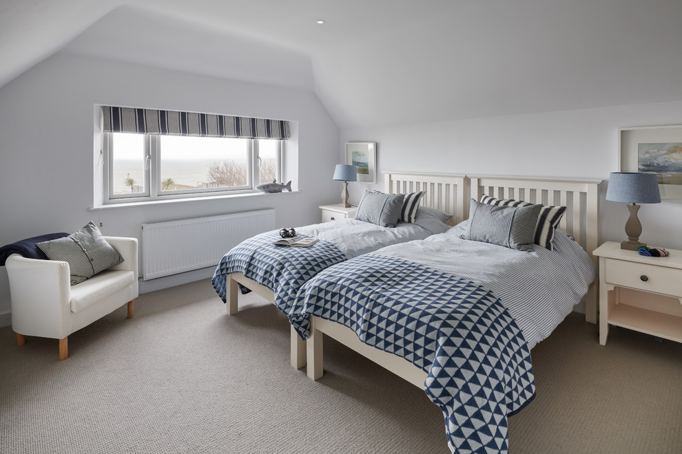 This is an example of a small beach style gender neutral kids' bedroom in Hampshire with white walls, carpet and grey floors.
