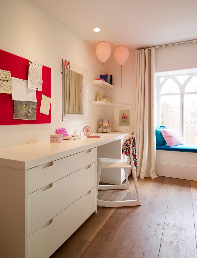 Imagen de habitación de niña actual con escritorio y suelo de madera en tonos medios