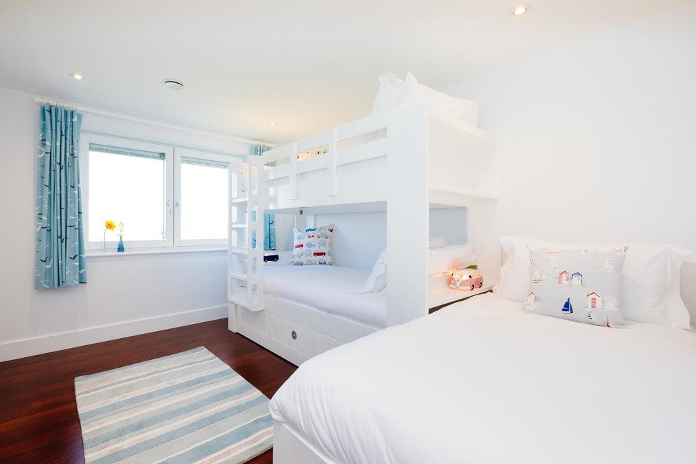 Example of a beach style gender-neutral kids' room design in Cornwall with white walls