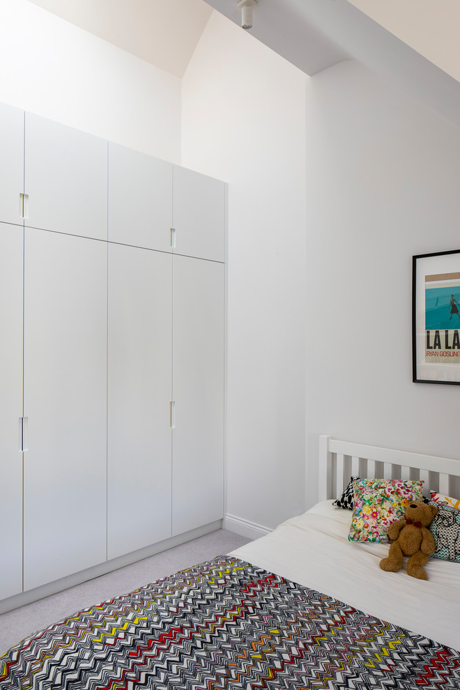 На фото: нейтральная детская среднего размера в стиле модернизм с рабочим местом, ковровым покрытием, серым полом, белыми стенами и сводчатым потолком для ребенка от 4 до 10 лет