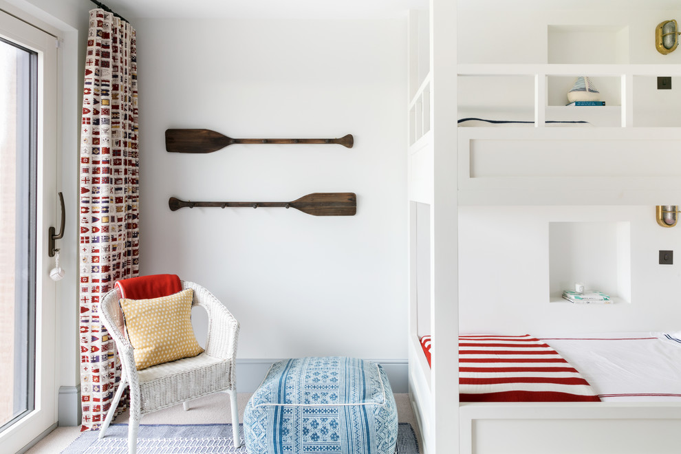 This is an example of a large nautical gender neutral children’s room in London with white walls and carpet.