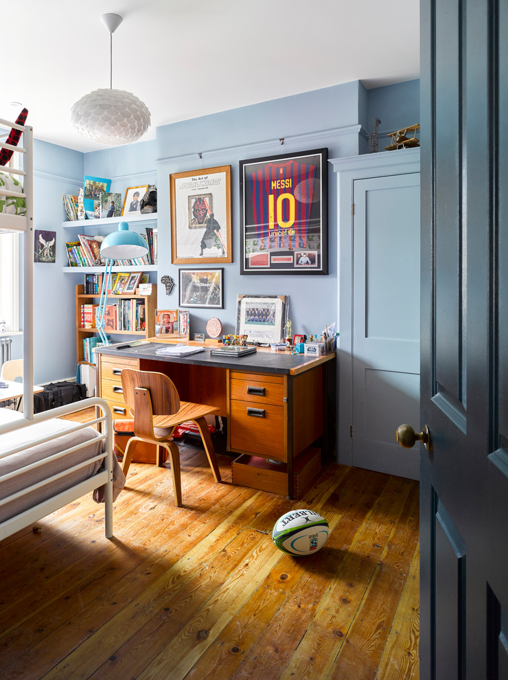 Imagen de habitación de niño de 4 a 10 años tradicional renovada de tamaño medio con escritorio, paredes azules, suelo de madera clara y suelo marrón
