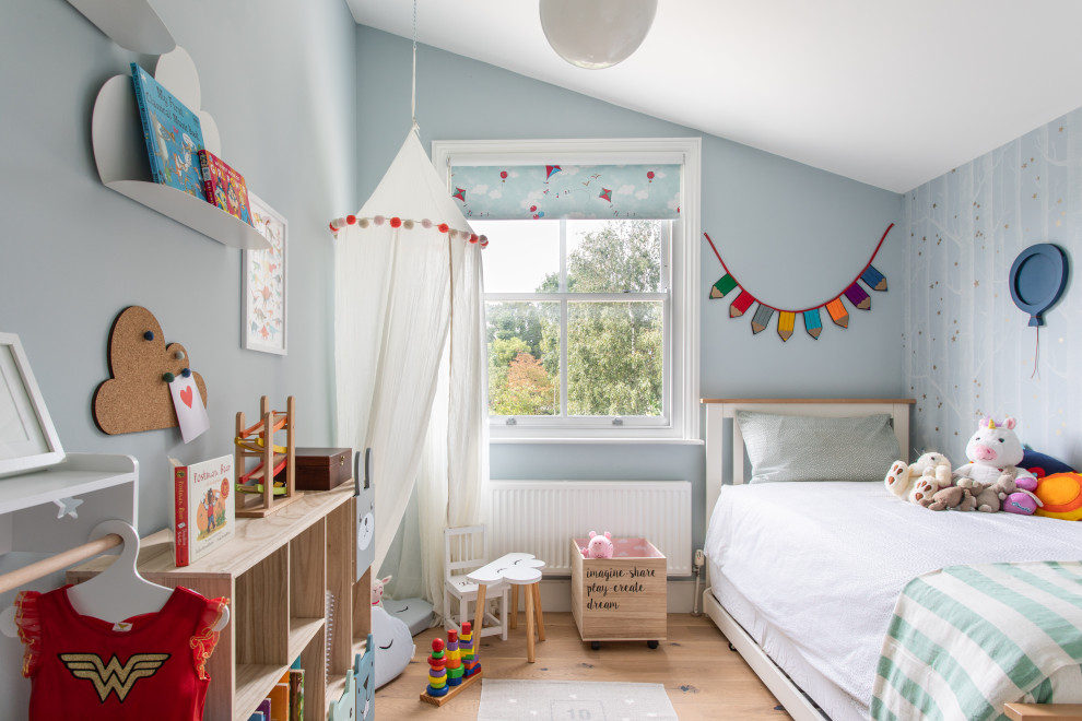 Immagine di una cameretta per bambini da 1 a 3 anni design di medie dimensioni con pareti blu, parquet chiaro e pavimento beige