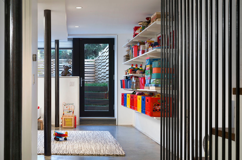 Photo of a contemporary playroom in New York with concrete flooring and white walls.