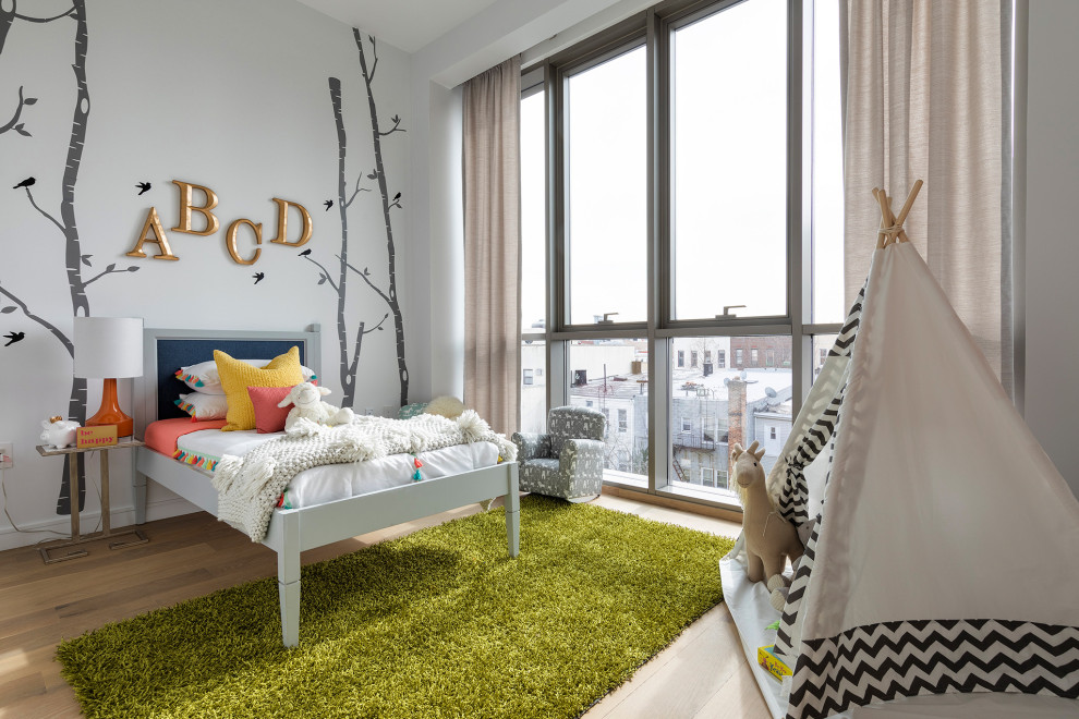 Trendy medium tone wood floor and brown floor kids' bedroom photo in New York with white walls