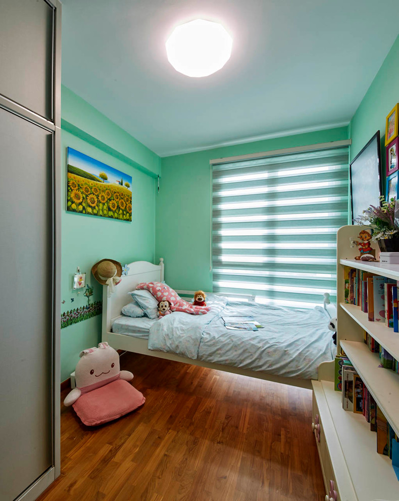 Esempio di una cameretta per bambini moderna di medie dimensioni con pareti verdi e pavimento in legno massello medio