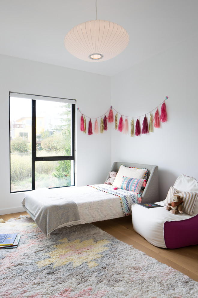 Imagen de dormitorio infantil de 1 a 3 años actual con paredes blancas y suelo de madera clara