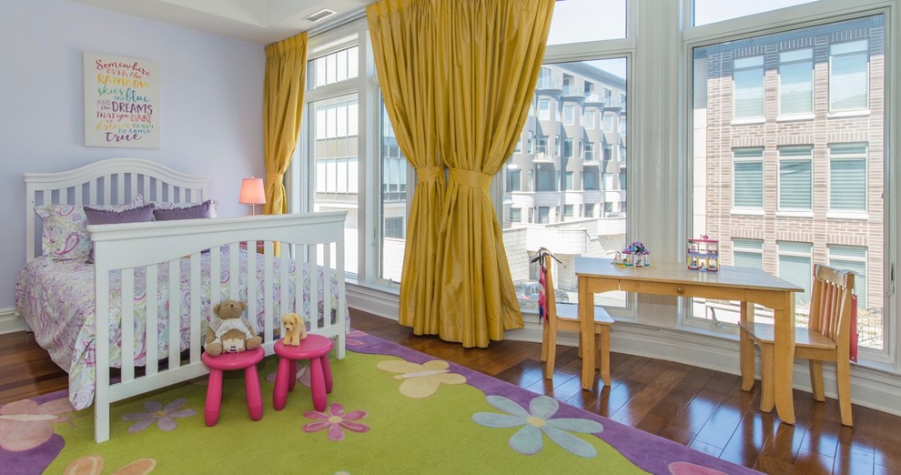 This is an example of a large traditional children’s room for girls in New York with purple walls, dark hardwood flooring and brown floors.