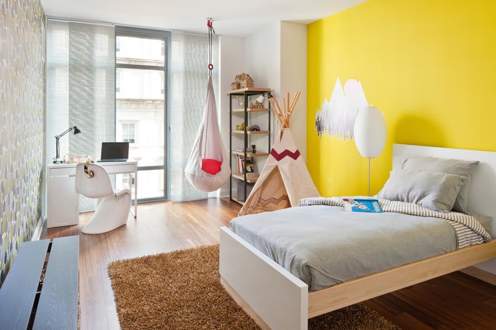 Photo of a medium sized traditional gender neutral children’s room in New York with yellow walls, medium hardwood flooring and brown floors.