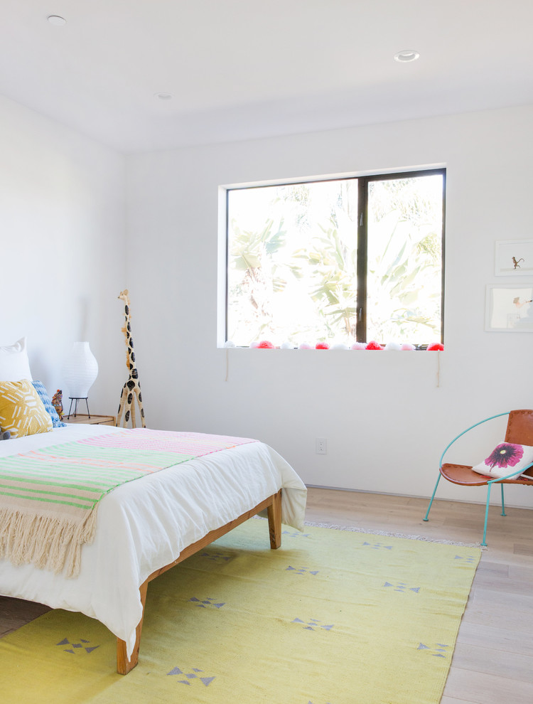 This is an example of a contemporary kids' bedroom for girls in Los Angeles with white walls, light hardwood flooring and beige floors.