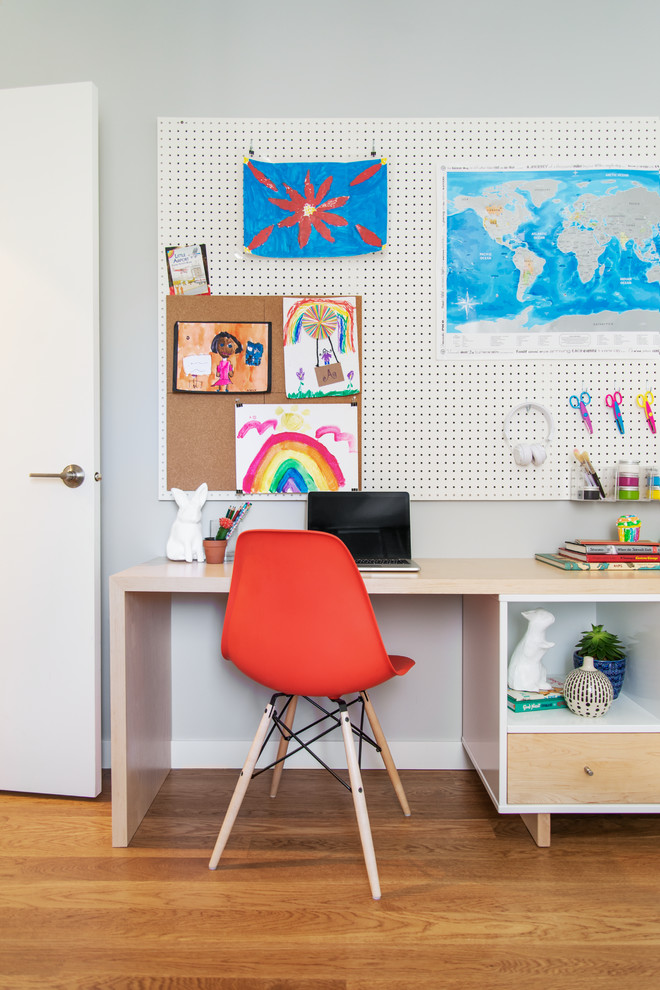 Cette image montre une chambre neutre de 4 à 10 ans design de taille moyenne avec un mur blanc, un sol en bois brun, un bureau et un sol marron.