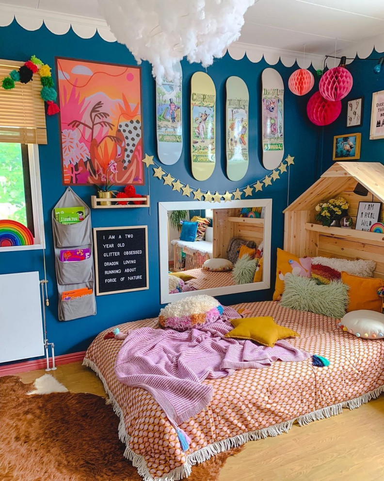 Foto di una cameretta per bambini da 1 a 3 anni eclettica con pareti blu, pavimento in legno massello medio e pavimento marrone