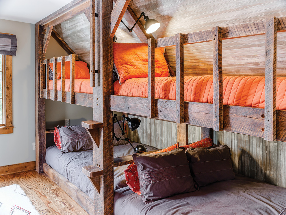 Immagine di una cameretta per bambini stile rurale con pavimento in legno massello medio, pavimento marrone e pareti grigie