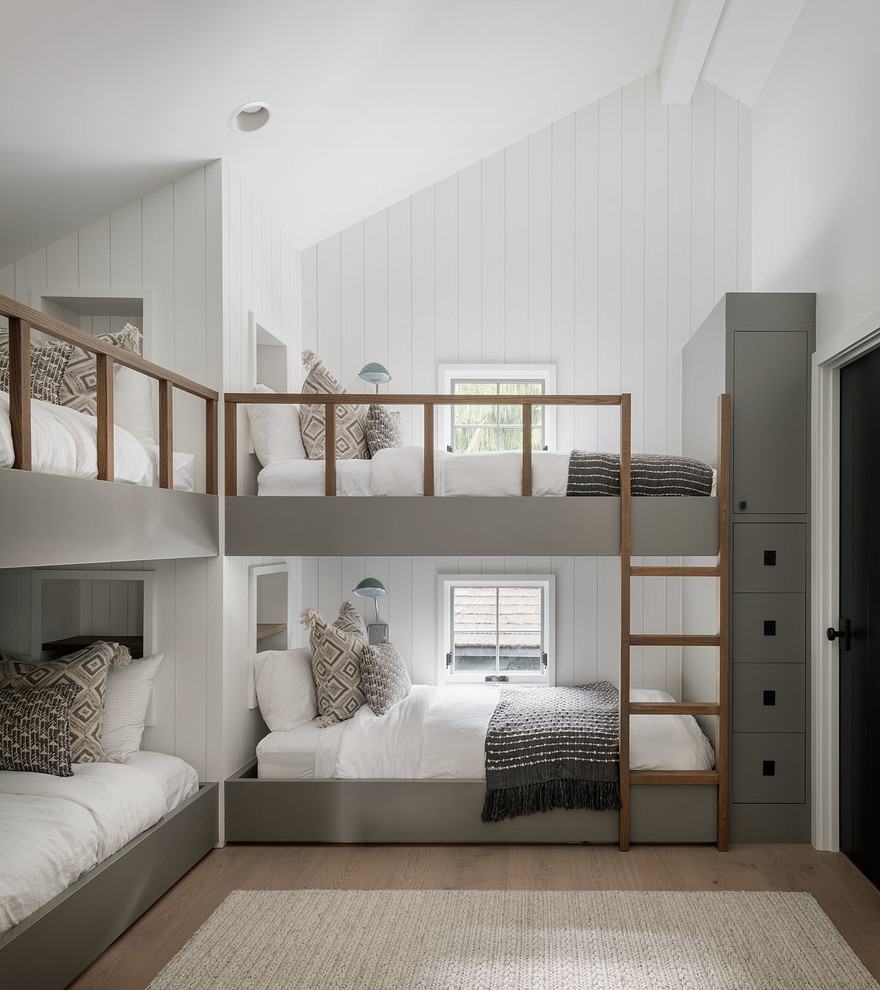 Immagine di una cameretta per bambini country con pareti bianche, pavimento in legno massello medio, pavimento marrone e pareti in perlinato