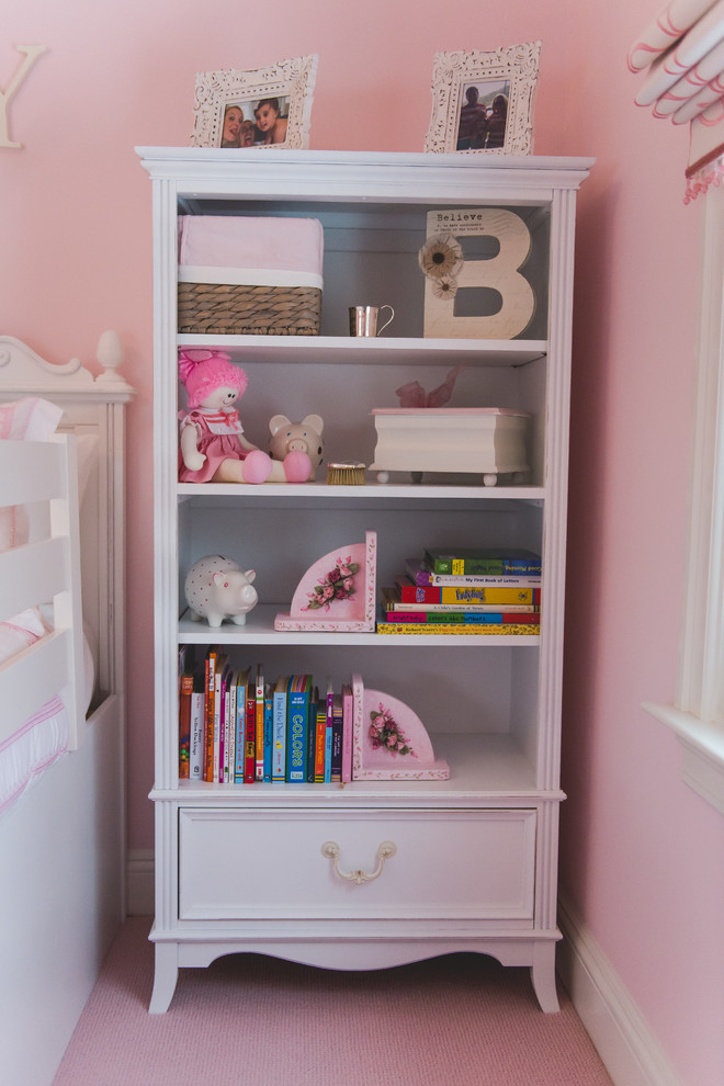 This is an example of a medium sized traditional children’s room for girls in New York with pink walls, carpet and pink floors.