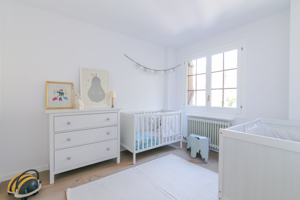 Foto på ett mellanstort minimalistiskt könsneutralt babyrum, med vita väggar och ljust trägolv