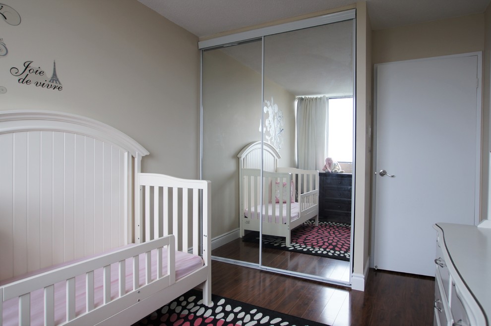 Small traditional toddler’s room for girls in Toronto with beige walls and vinyl flooring.