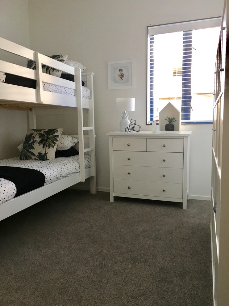 Inredning av ett modernt litet könsneutralt barnrum kombinerat med sovrum och för 4-10-åringar, med vita väggar, heltäckningsmatta och grått golv