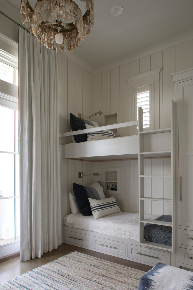 Cette image montre une chambre d'enfant marine avec un mur blanc, parquet foncé, un sol marron et un lit superposé.