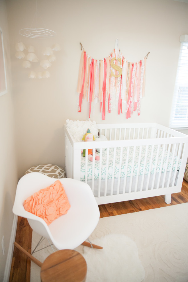 Inspiration for a mid-sized transitional girl medium tone wood floor nursery remodel in Orange County with beige walls