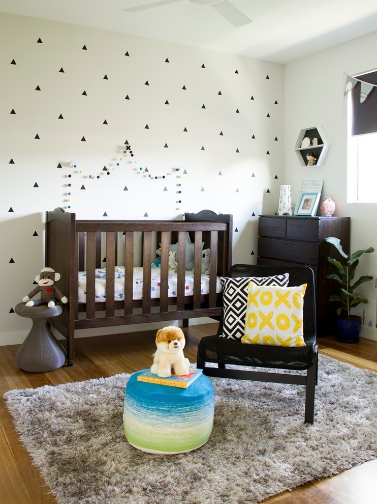 Diseño de habitación de bebé niño actual de tamaño medio con paredes beige y suelo de madera clara
